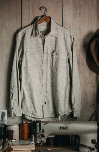 The Utility Shirt in Japanese Kuroki Natural Nep hanging on a cabin wall in front of a sewing machine