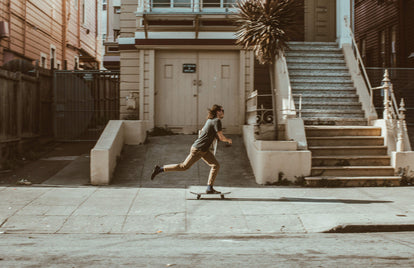 Skateboarder, pushing through the city streets.