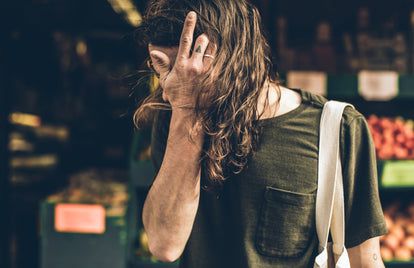Casual cool, long-hair getting tucked back by a tattooed finger, carrying produce home.