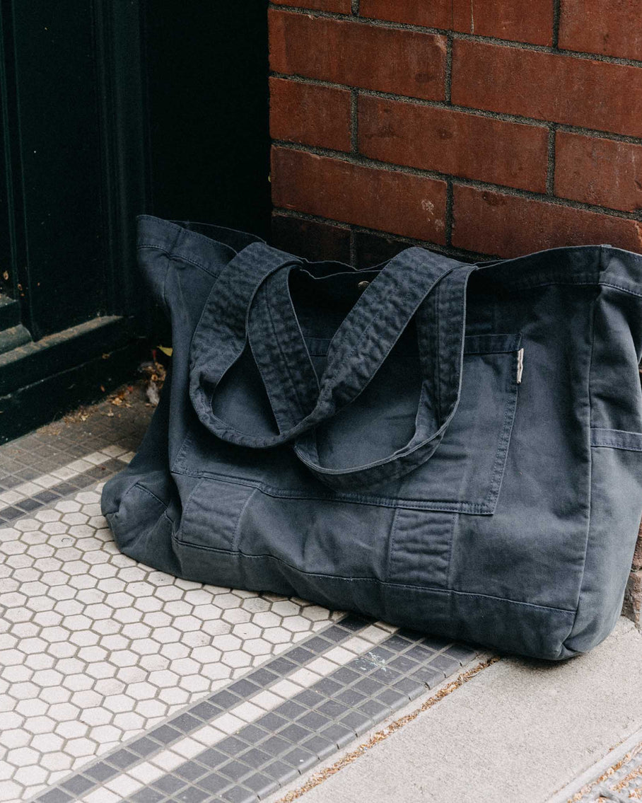 editorial image of The Foundation Tote in Organic Navy leaning against the wall, Accessories by Taylor Stitch