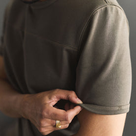 fit model adjusting the sleeves on The Rugby Tee in Smoked Olive