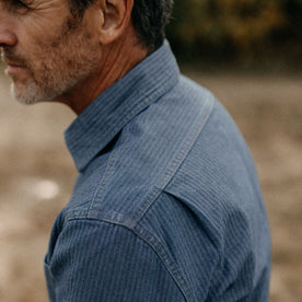 fit model showing the back pleat on The Utility Shirt in Washed Indigo Herringbone