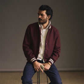 fit model sitting on a stool wearing The Golden Bear Snap Bomber in Port Wool