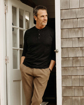fit model leaning against the door wearing The Merino Henley in Heather Black, Knits by Taylor Stitch