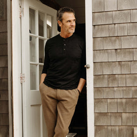 fit model leaning against the door wearing The Merino Henley in Heather Black