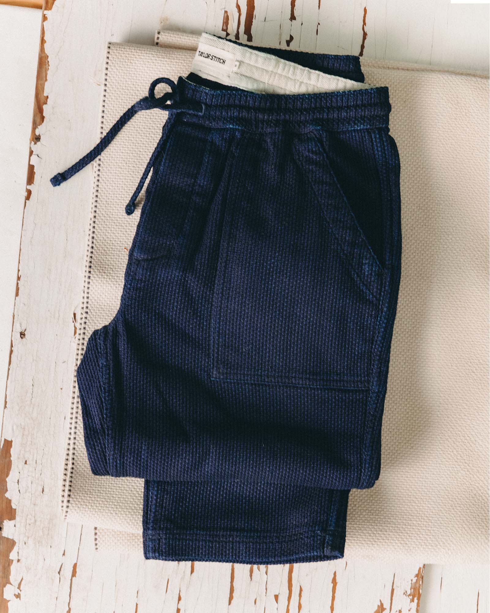 editorial flatlay of The Breakwater Pant in Rinsed Indigo Sashiko, Bottoms by Taylor Stitch