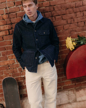 fit model leaning against the wall wearing The Fremont Jacket in Rinsed Indigo Dobby Denim, Outerwear by Taylor Stitch