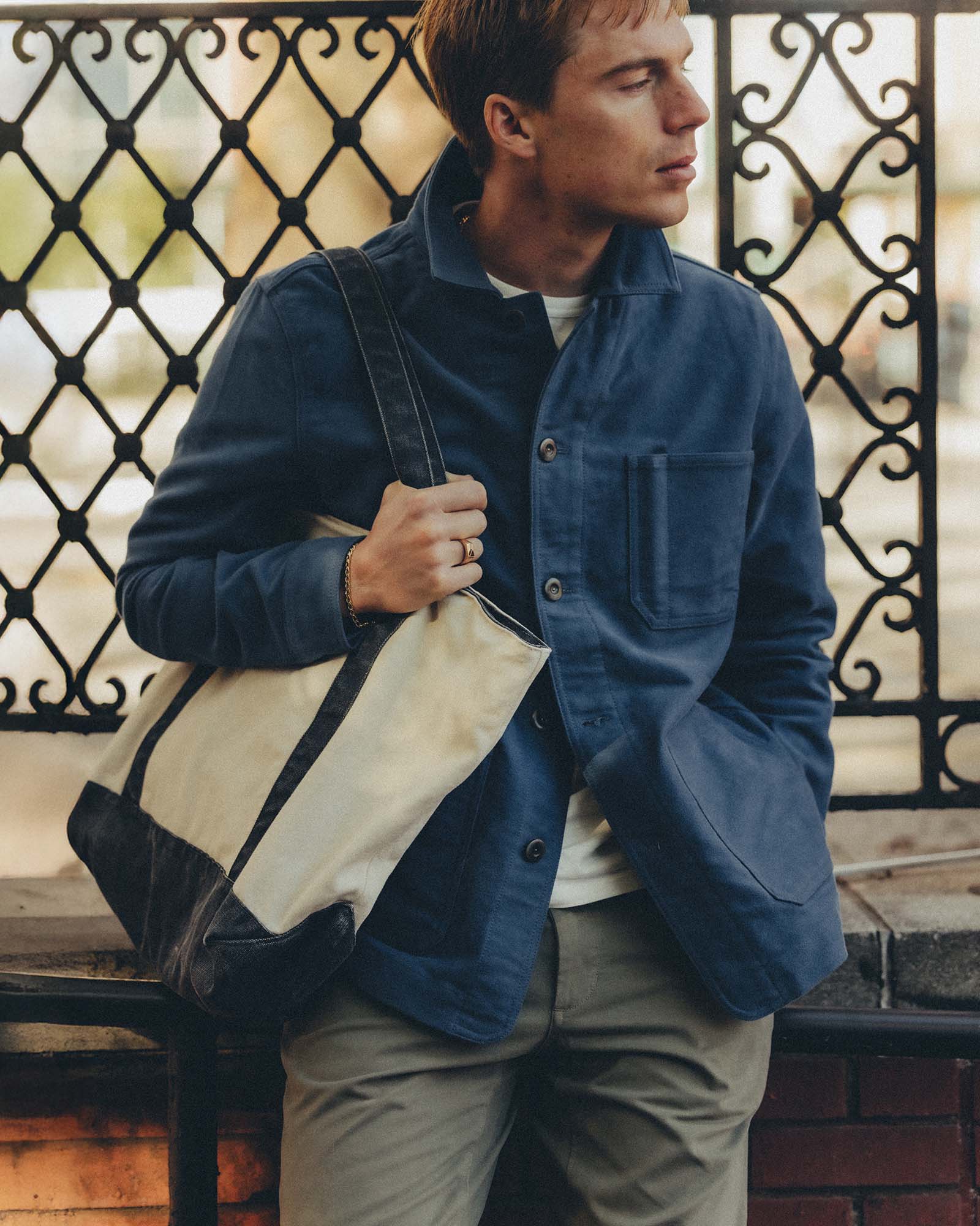 fit model leaning against the wall wearing The Schooner Tote in Seeded Natural Chipped Canvas, Accessories by Taylor Stitch