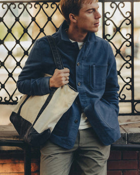 fit model leaning against the wall wearing The Schooner Tote in Seeded Natural Chipped Canvas, Accessories by Taylor Stitch