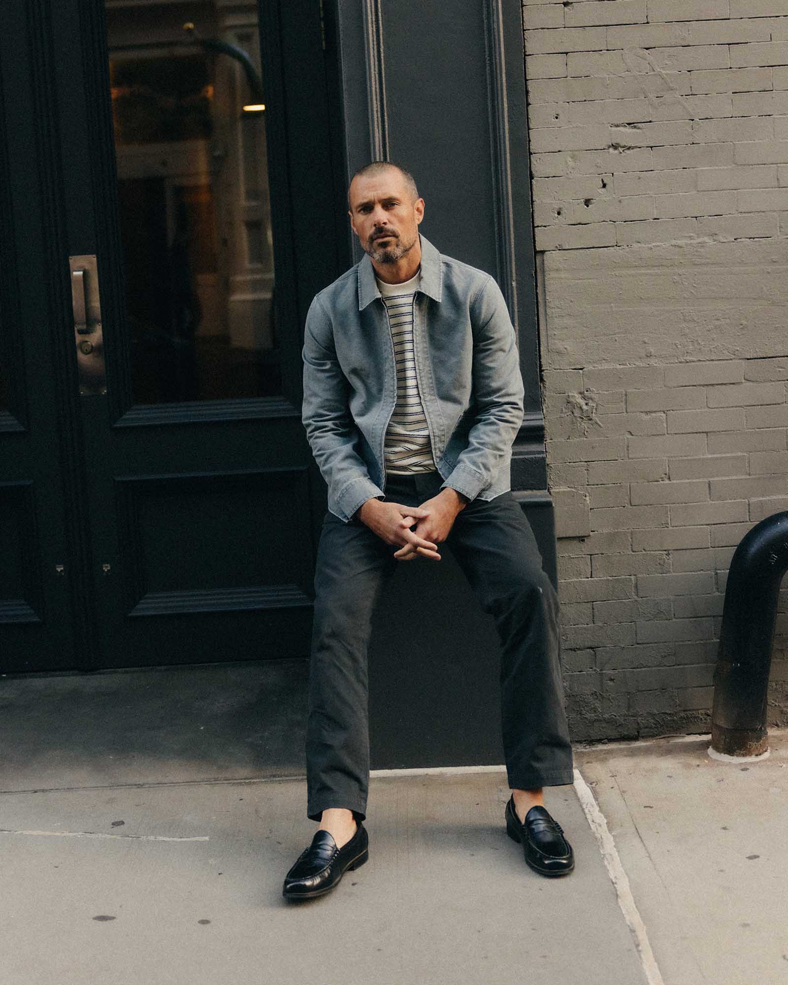 fit model sitting wearing The Straight Foundation Pant in Organic Faded Black, Bottoms by Taylor Stitch