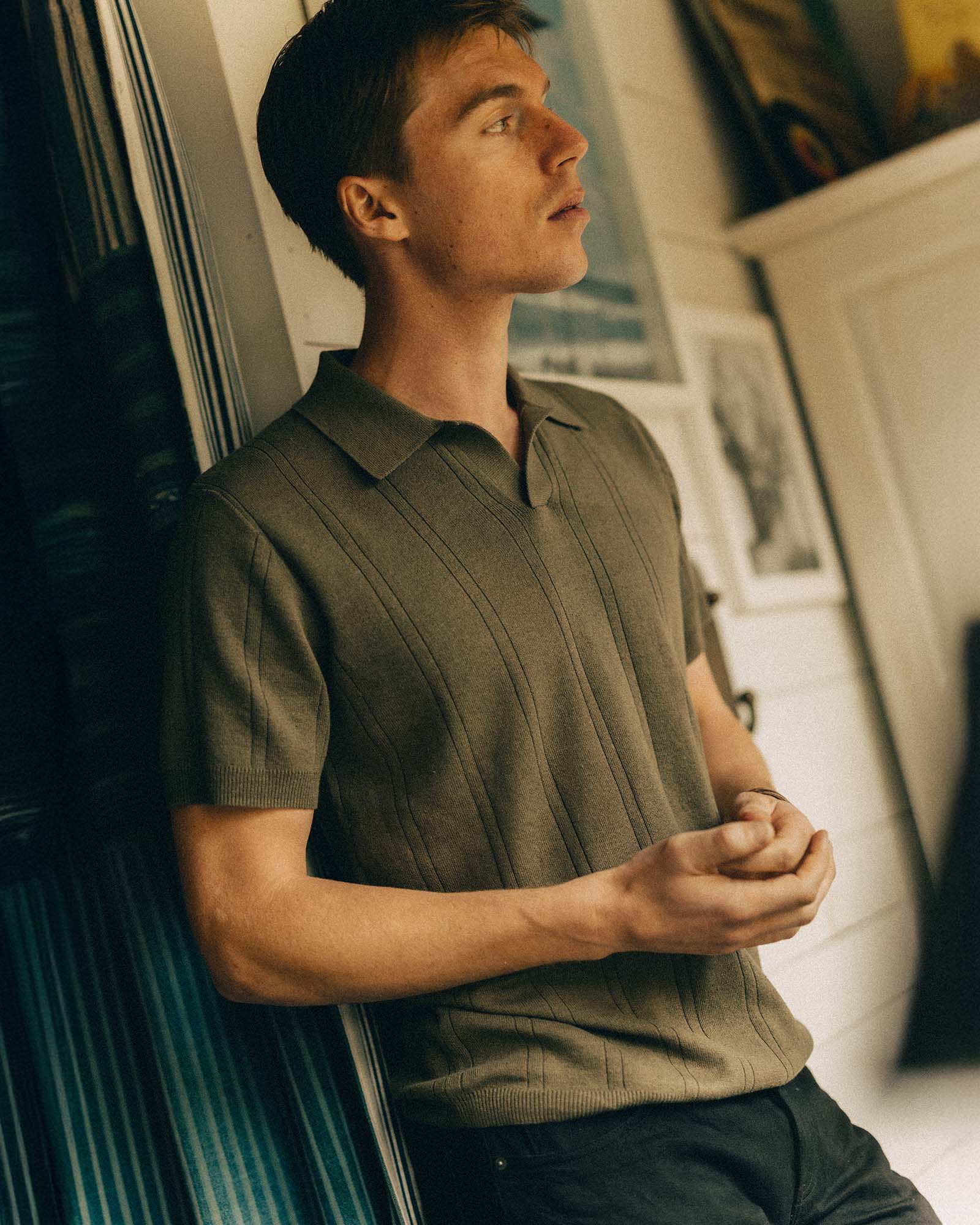 fit model leaning against the wall wearing The Valencia Sweater Polo in Heather Cilantro Rib, Knits by Taylor Stitch