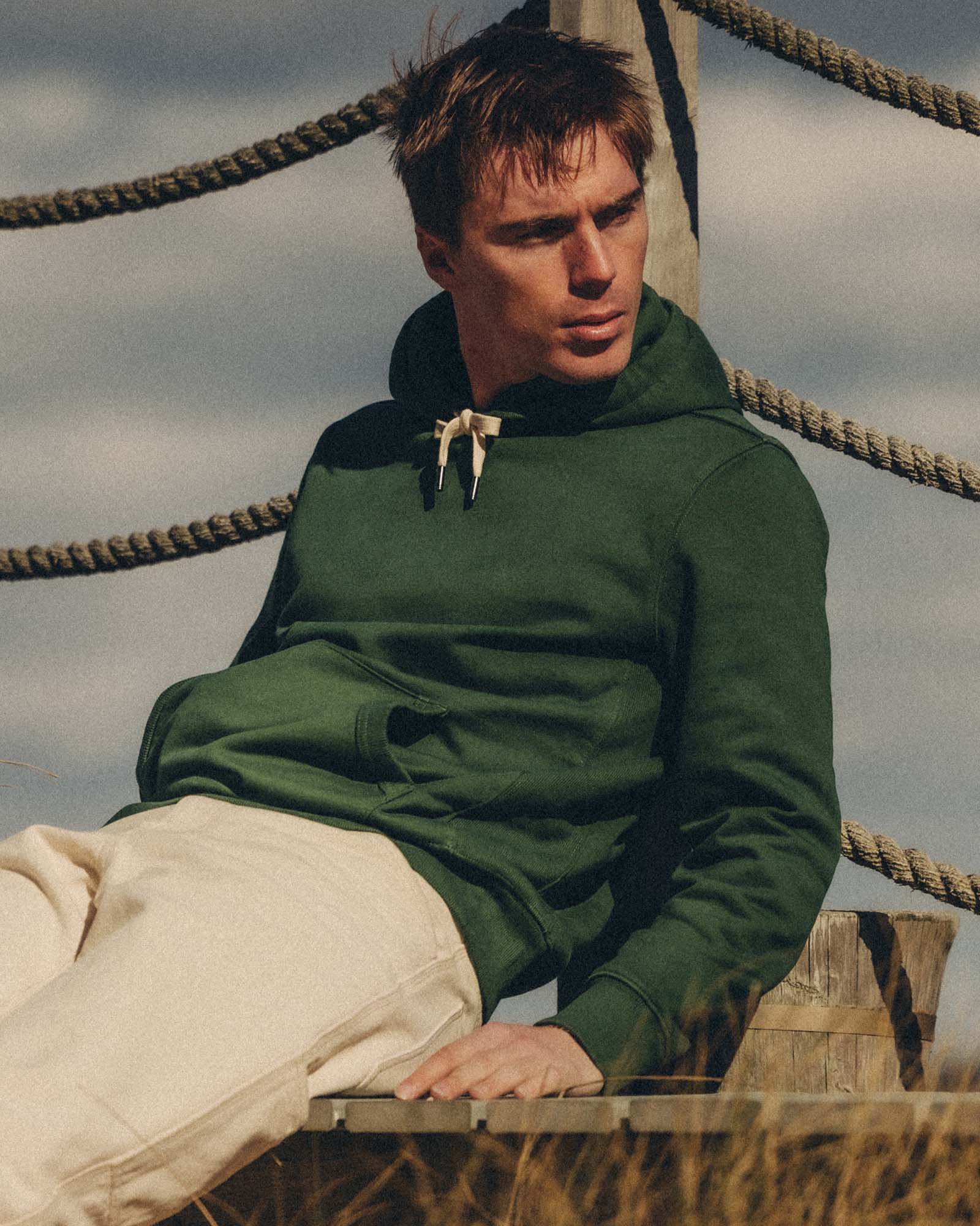 fit model sitting wearing The Shop Hoodie in Ivy French Terry, Knits by Taylor Stitch