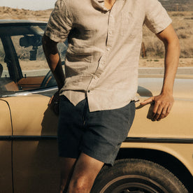 fit model leaning against a car in The Apres Short in Granite Hemp