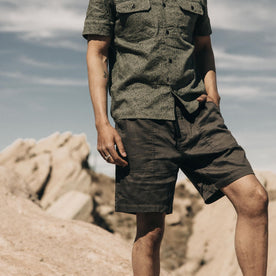 fit model standing amidst boulders in The Apres Trail Short in Granite Double Cloth
