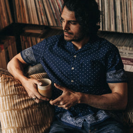 fit model sitting on a couch in The Short Sleeve Hawthorne in Indigo Star Dot Border