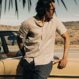 fit model sitting on the hood of a vintage car in The Short Sleeve California in Sage Hemp