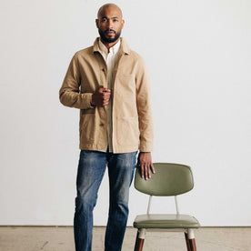 fit model leaning against a chair wearing The Ojai Jacket in Organic Light Khaki Foundation Twill
