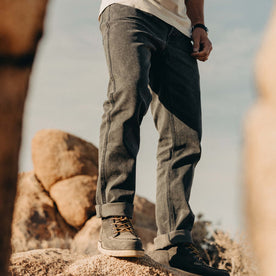 fit model standing on a rock wearing The Camp Pant in Coal Chipped Canvas