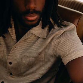fit model sitting in a car wearing The Conrad Shirt in Black Coffee Stripe