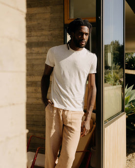 fit model leaning against the wall wearing The Cotton Hemp Tee in Heather Oat, Knits by Taylor Stitch