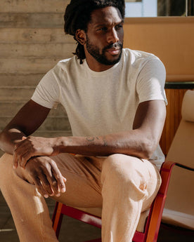 fit model sitting on a chair wearing The Cotton Hemp Tee in Heather Oat, Knits by Taylor Stitch