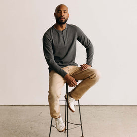 fit model sitting on a stool wearing The Heavy Bag Henley in Heather Grey
