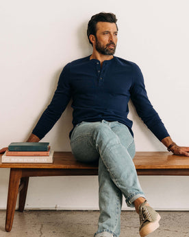 fit model sitting on a bench wearing The Heavy Bag Henley in Navy, Knits by Taylor Stitch