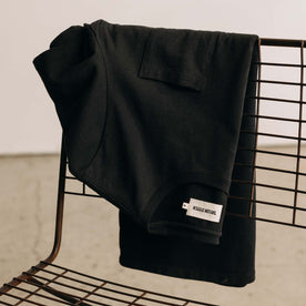 editorial image of The Heavy Bag Tee in Black on a chair