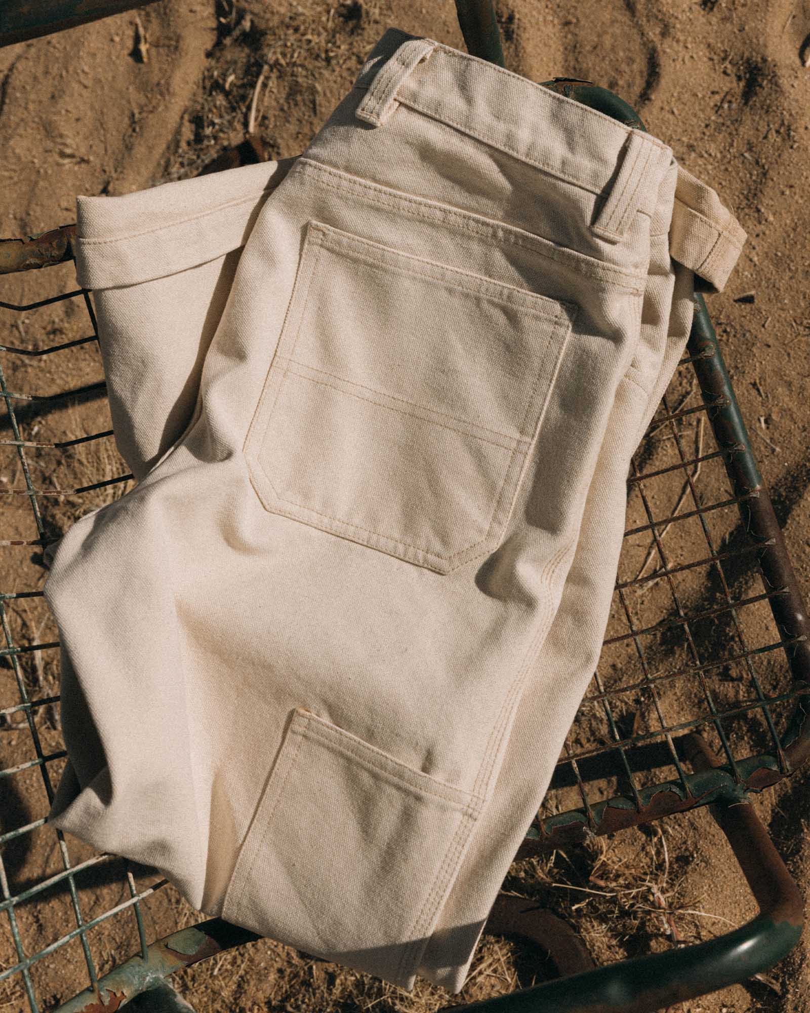 editorial flatlay of The Painter Pant in Seeded Natural Chipped Canvas on a chair, Bottoms by Taylor Stitch
