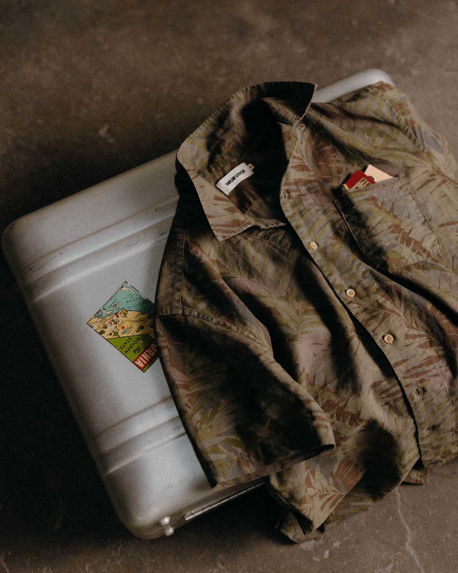 editorial image of The Hawthorne Shirt in Fatigue Olive Desert Palm on a suitcase, Wovens by Taylor Stitch