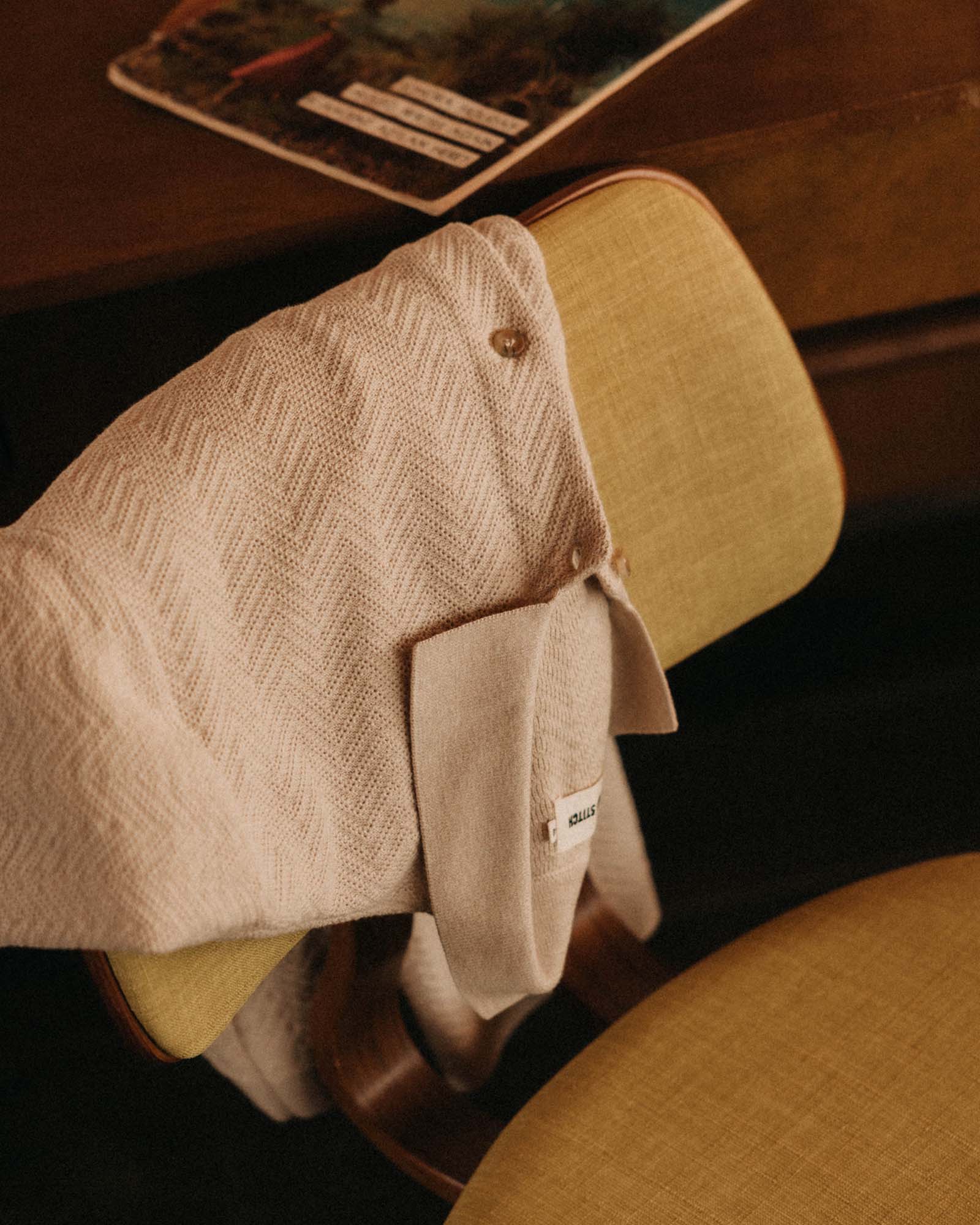 editorial image of The Button Down Polo in Heather Oat Herringbone on a chair, Knits by Taylor Stitch