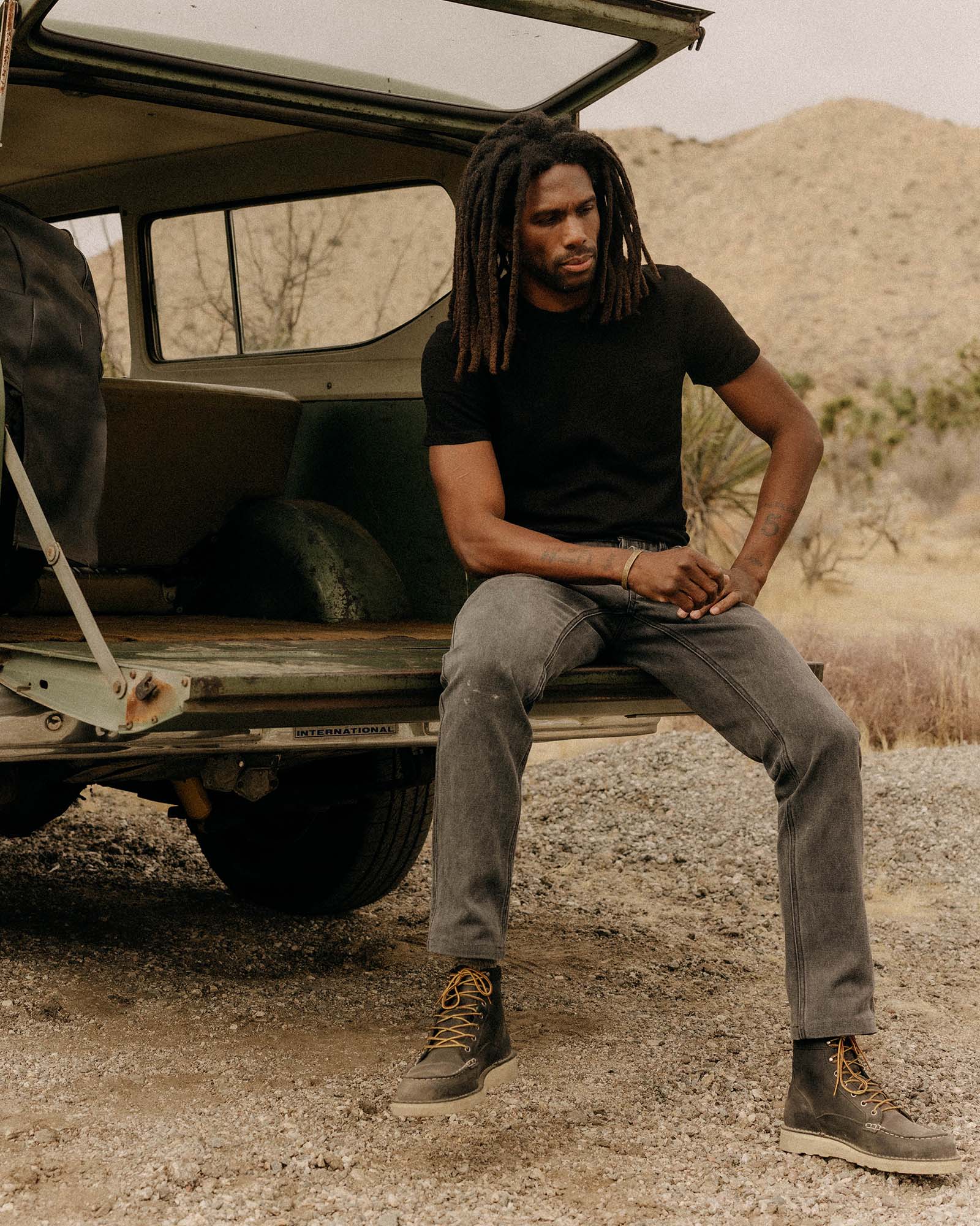 fit model sitting in a car wearing The Organic Cotton Tee in Black Indigo, Knits by Taylor Stitch