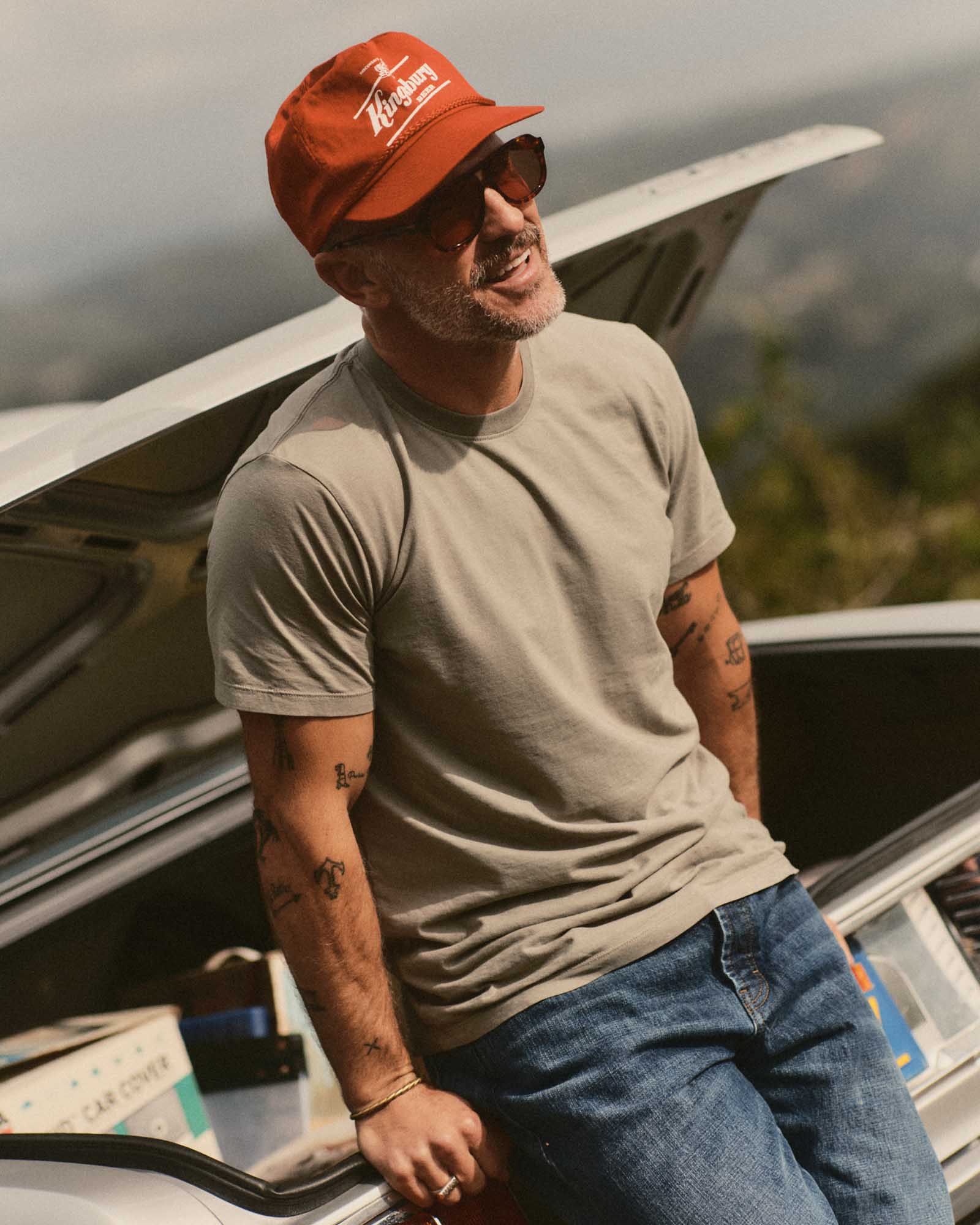 fit model leaning against a car wearing The Cotton Hemp Tee in Sage, Knits by Taylor Stitch