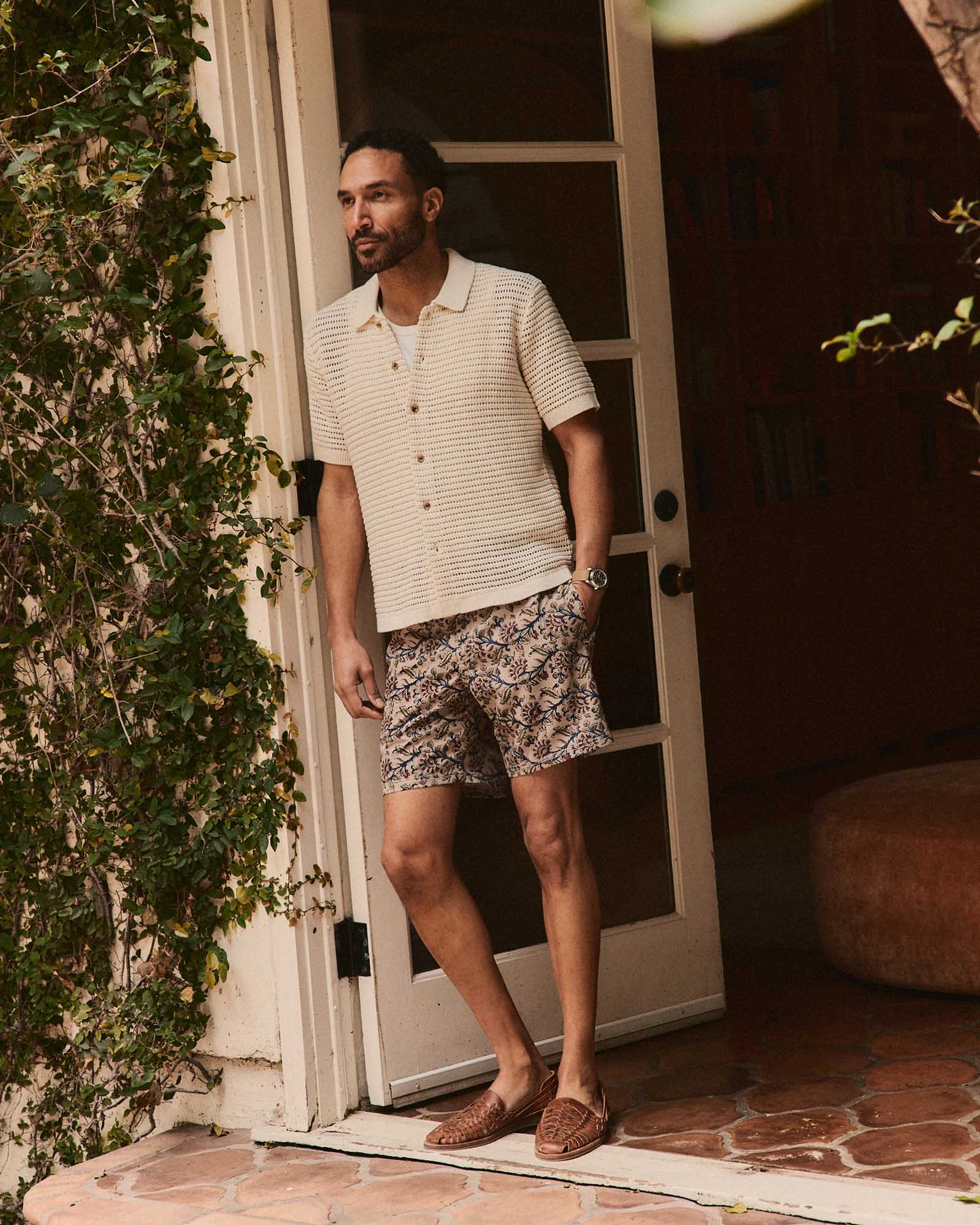 fit model leaning against the wall wearing The Drift Boardshort in Ivory Floral, Bottoms by Taylor Stitch