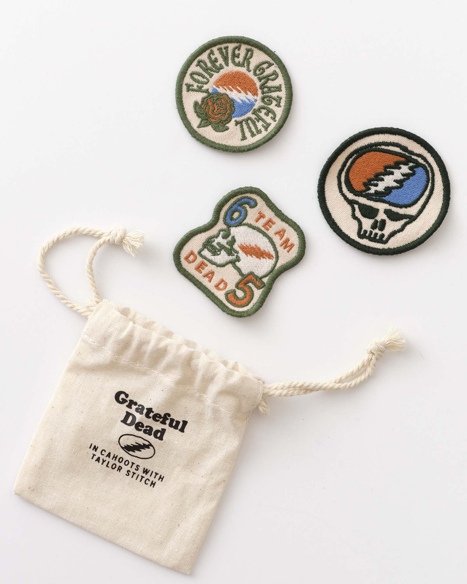 Three Grateful Dead-themed patches on a white background with a small drawstring bag., Accessories by Taylor Stitch