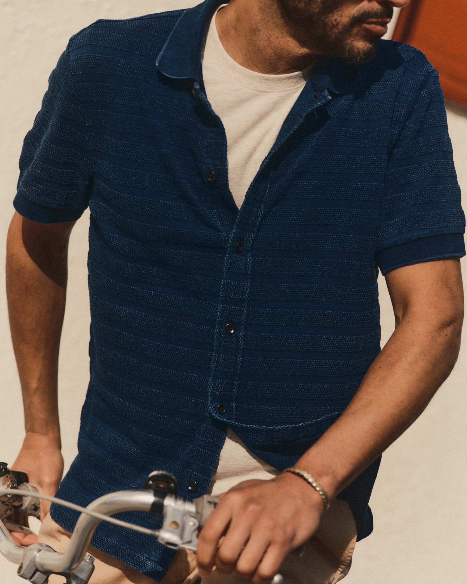 fit model on a bike wearing The Bywater Polo in Rinsed Indigo Knit Stripe, Knits by Taylor Stitch