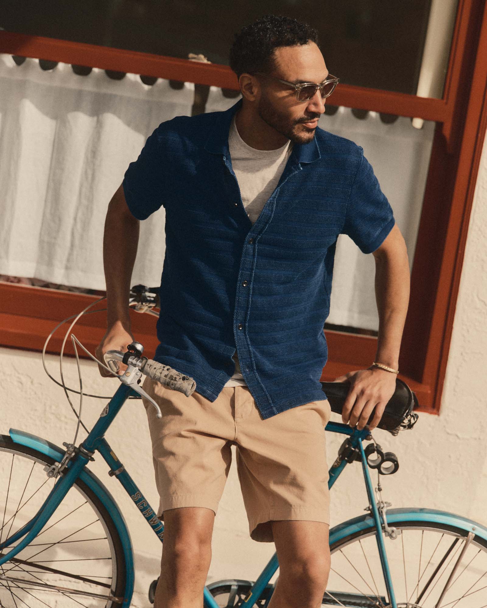 fit model sitting on a bike wearing The Bywater Polo in Rinsed Indigo Knit Stripe, Knits by Taylor Stitch