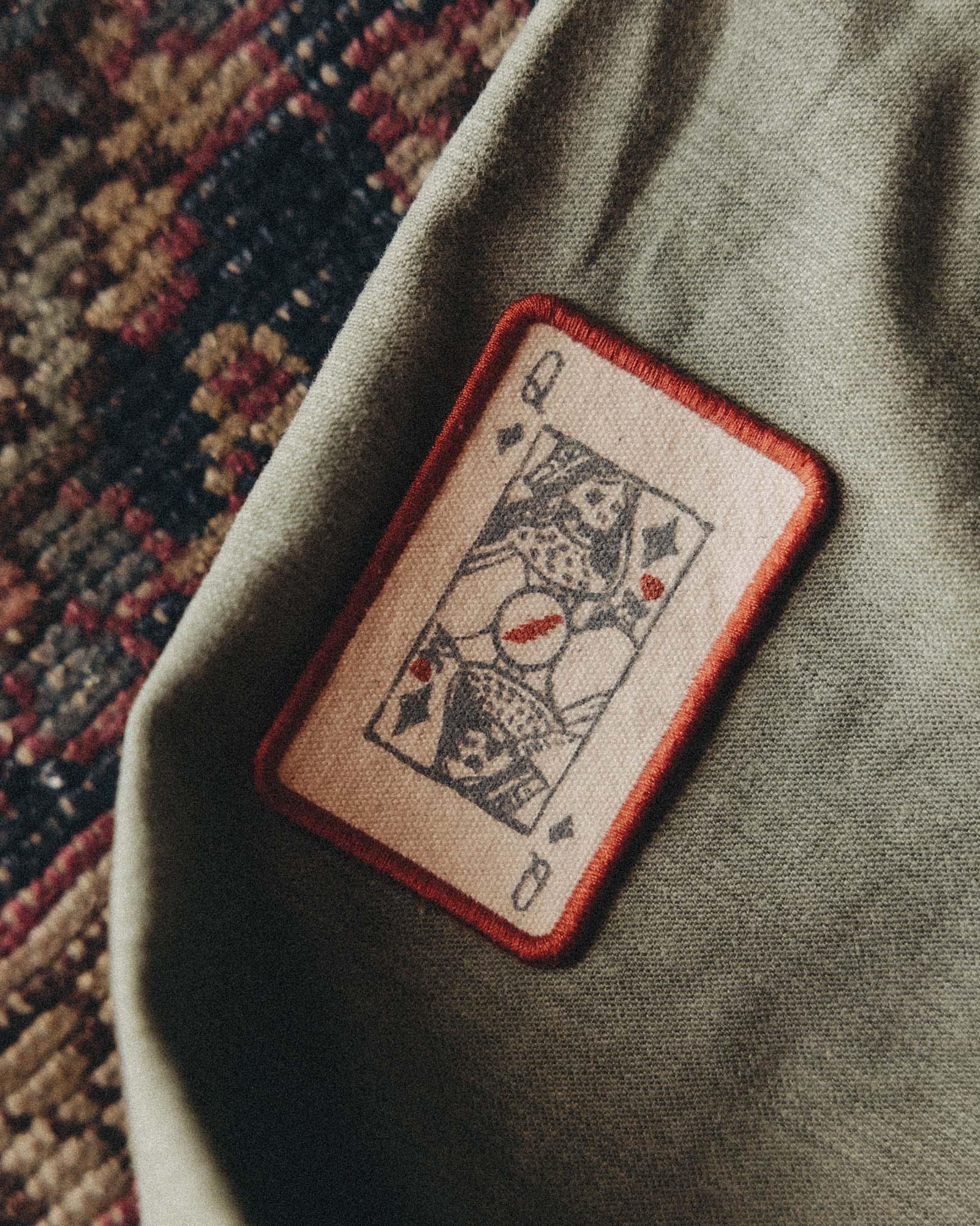 Patch of a playing card on a green fabric background, Accessories by Taylor Stitch