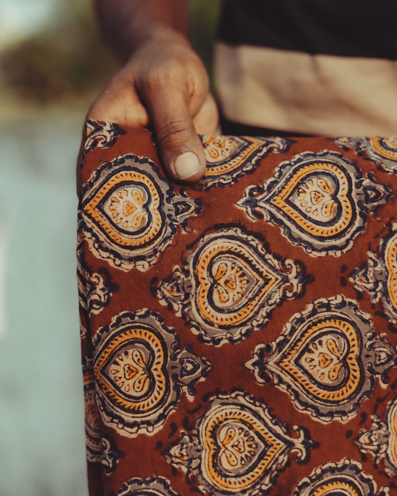 designer holding the fabric of The Hawthorne Shirt in Sangria Block Print, Wovens by Taylor Stitch