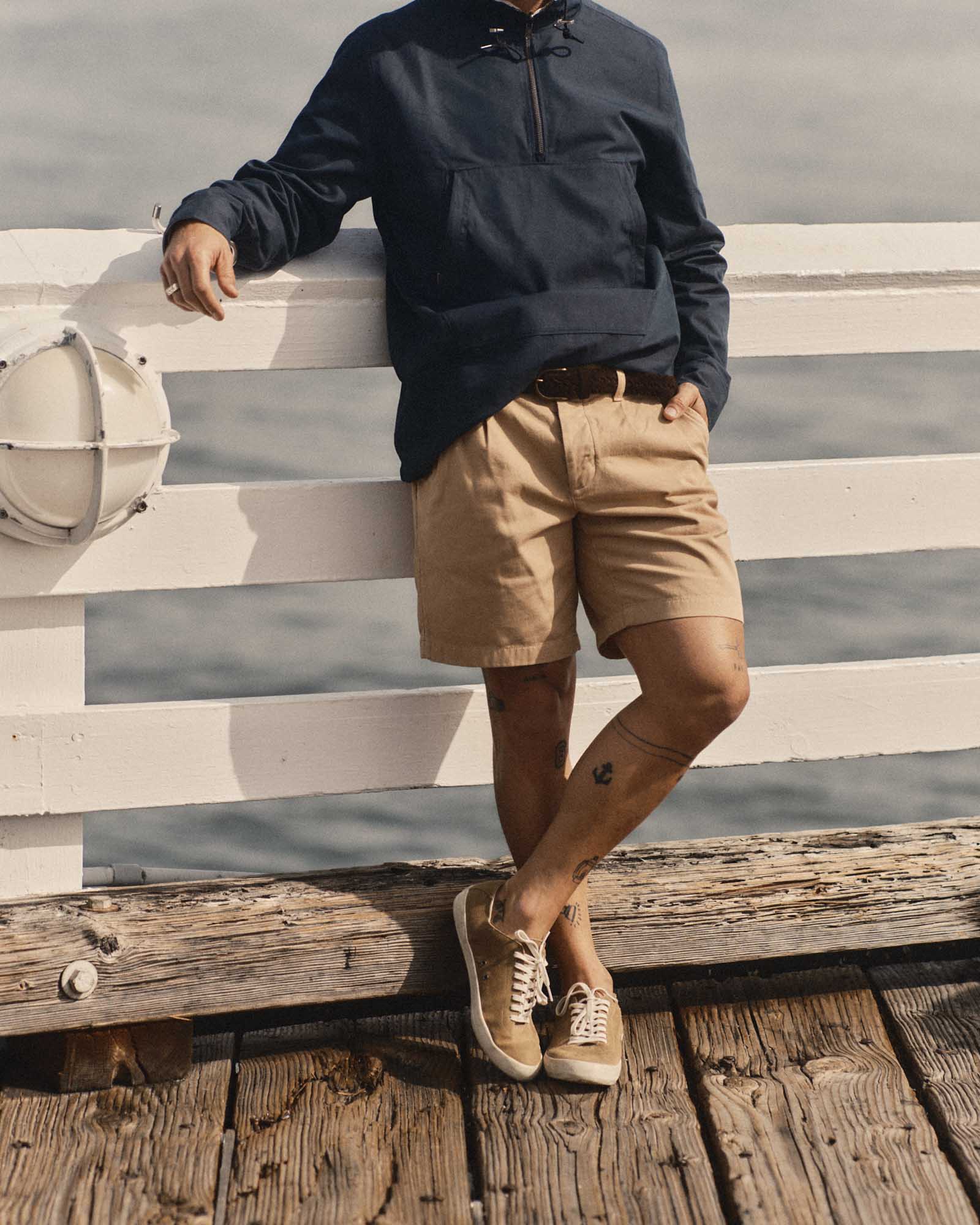 fit model leaning against the railing wearing The Pleated Short in Organic Field Khaki Twill, Bottoms by Taylor Stitch