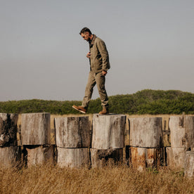 fit model standing on logs in The Chore Pant in Stone Boss Duck