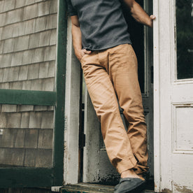 fit model leaning against the wall wearing The Democratic All Day Pant in Tobacco Selvage Denim