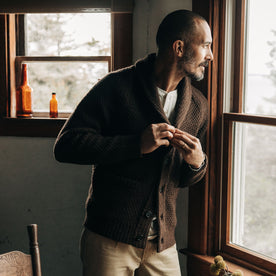 fit model buttoning up The Fisherman Shawl Cardigan in Marsh Heather