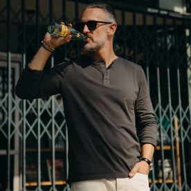 fit model with his arms folded wearing The Organic Cotton Henley in Faded Black