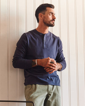 fit model leaning against the wall wearing The Organic Cotton Henley in Navy, Knits by Taylor Stitch