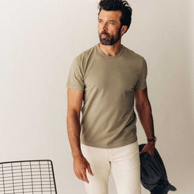 fit model sitting leaning against the wall in The Organic Cotton Tee in Sage
