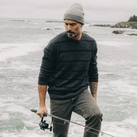 fit model holding a fishing rod in The Lodge Sweater in Charcoal Stripe