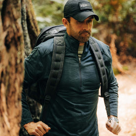 fit model adjusting backpack wearing The Merino Half Zip in Forest