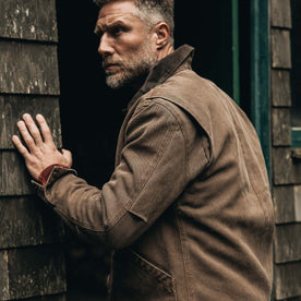 fit model holding the wall wearing The Workhorse Jacket in Aged Penny Chipped Canvas