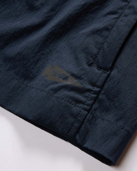 material shot of the brand tag on The Deploy Packable Shell in Dark Navy, Outerwear by Taylor Stitch